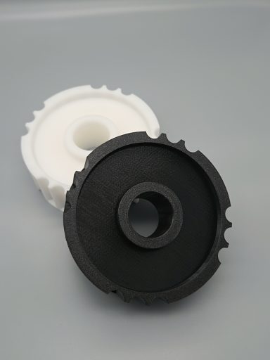 Schwarze und weiße Zahnräder aus Kunststoff, übereinandergelegt, mit zentralem Loch.